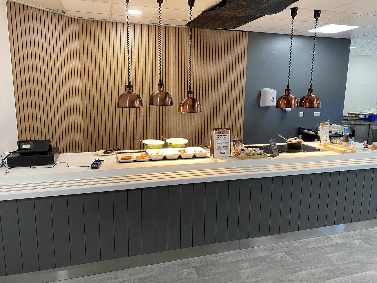 Servery counter with timber slatted wall and copper pendant lights