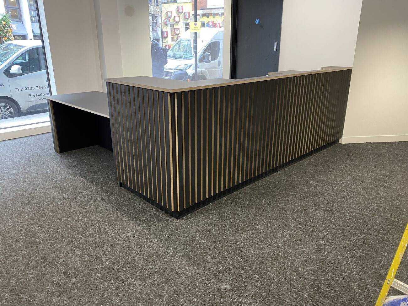 Dark slatted reception desk installed in a modern interior