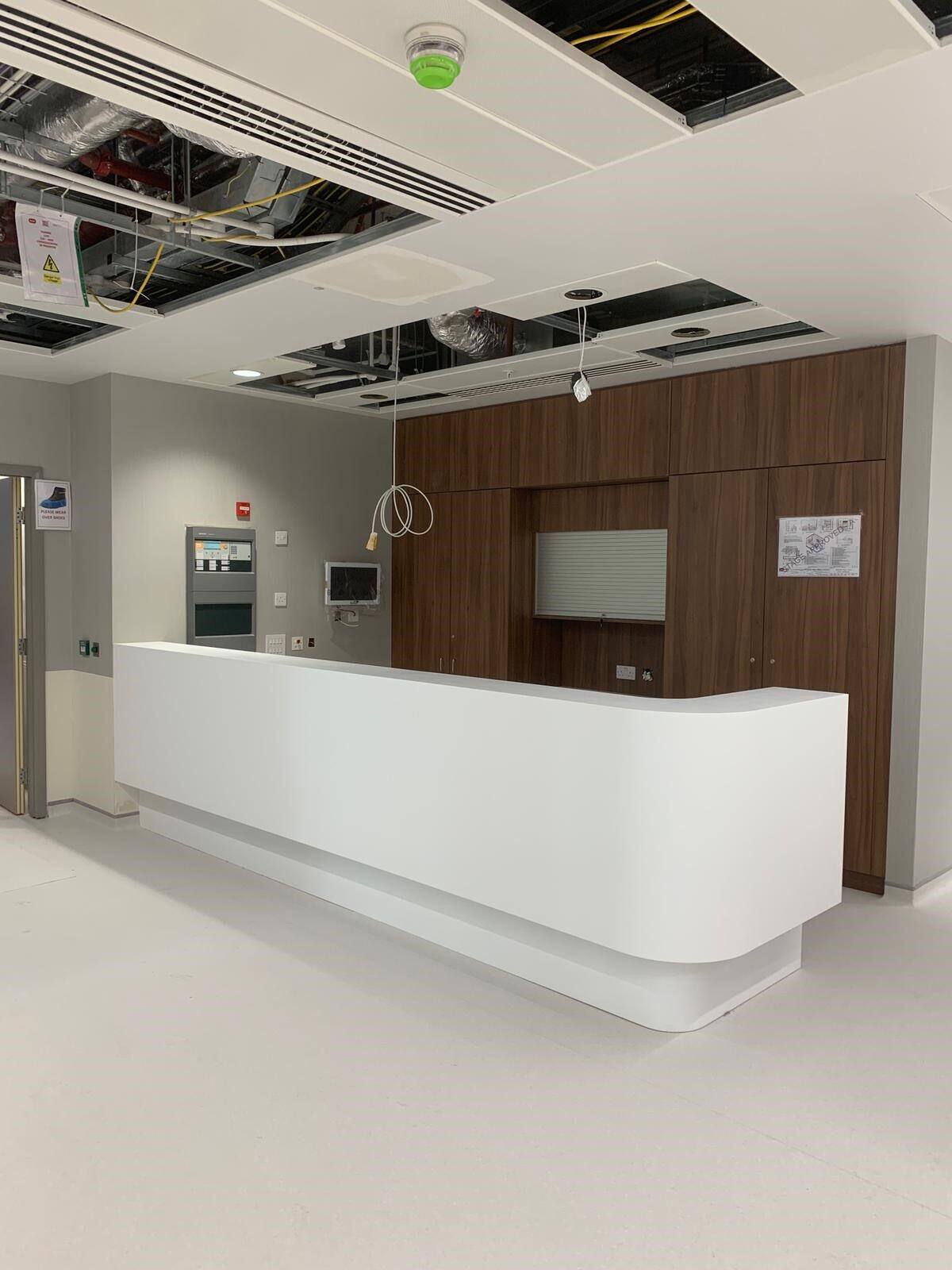 White solid surface healthcare reception counter with walnut panelling