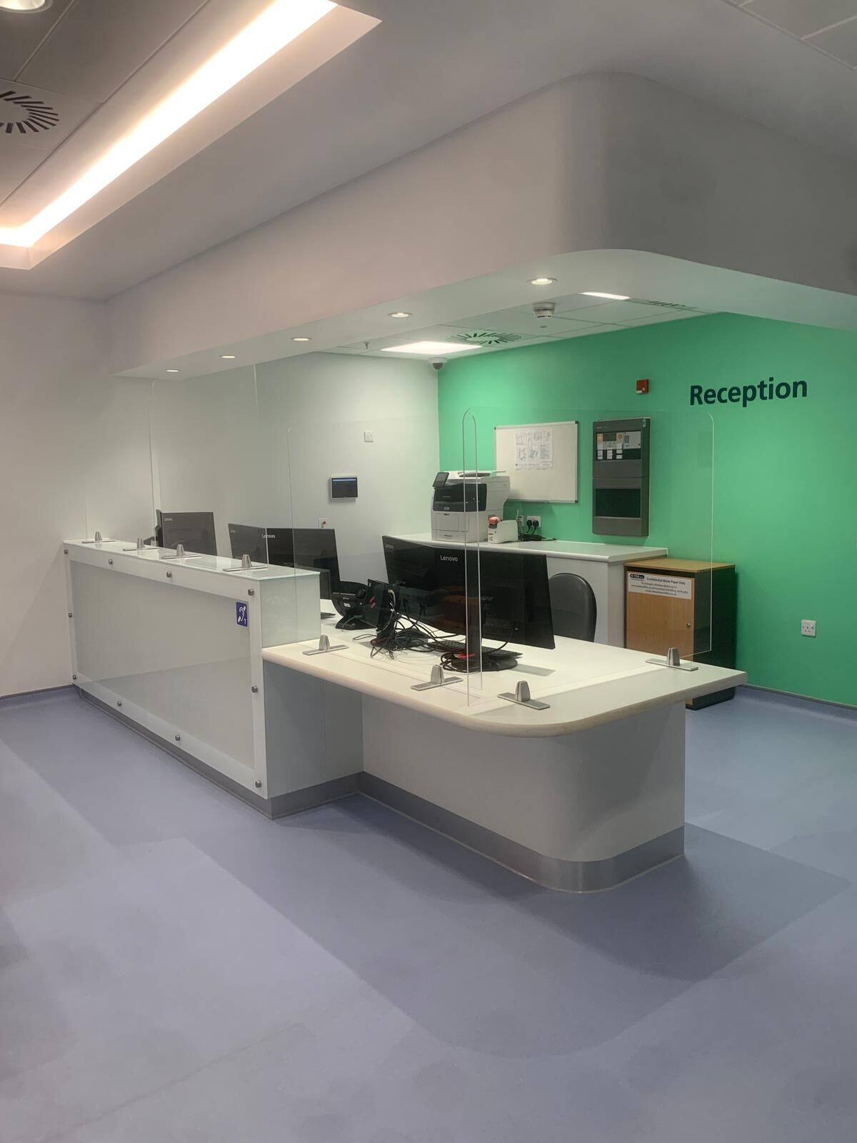Curved reception desk in a healthcare building with green feature wall