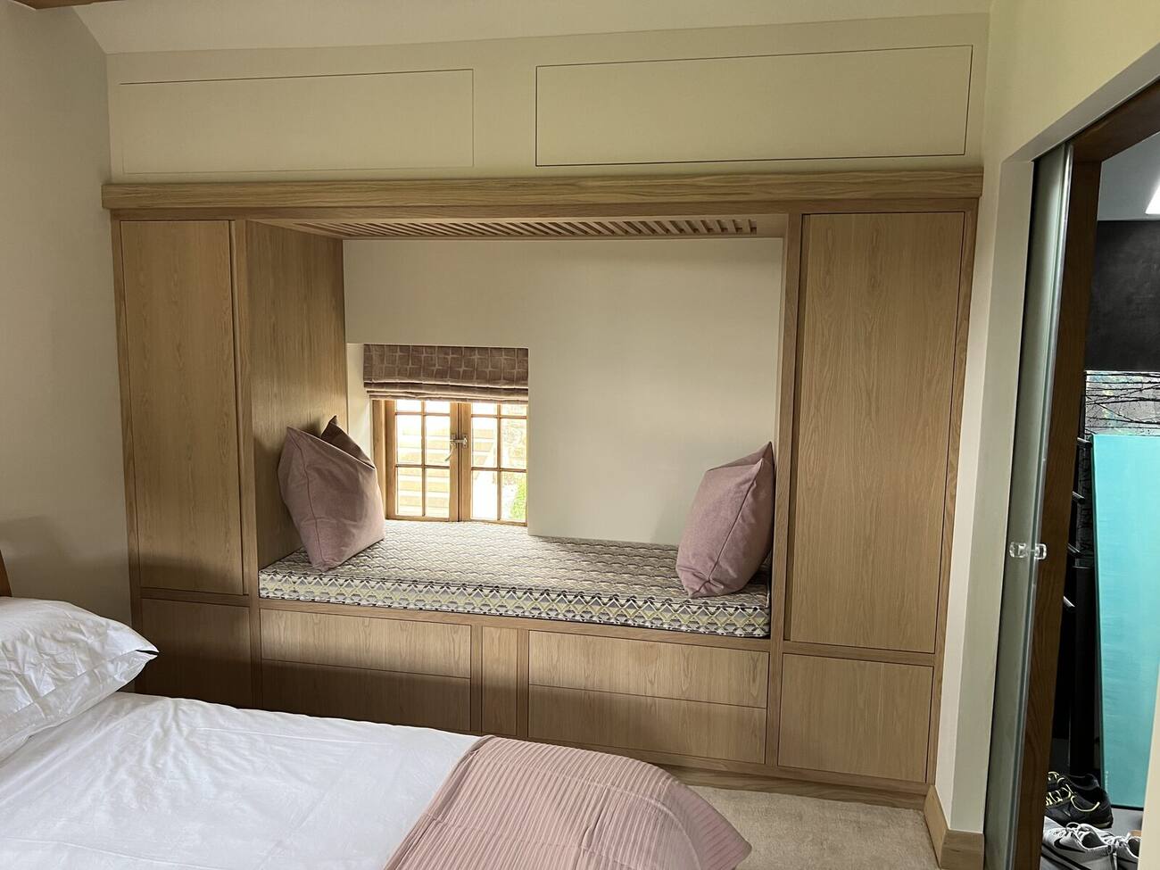 Oak fitted window seat with cushions in a bedroom
